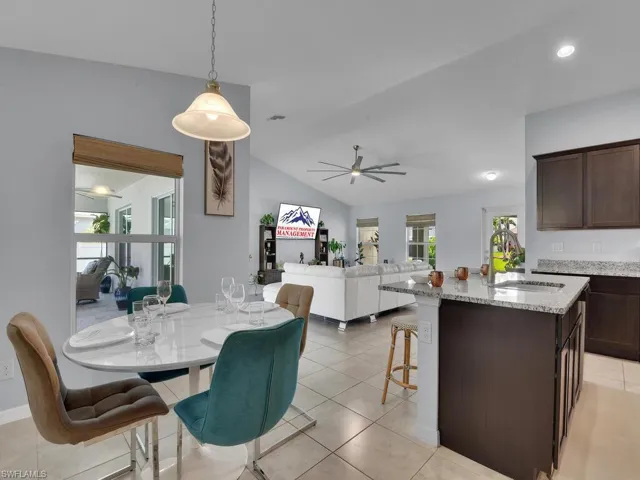 Tiled dining room featuring ceiling fan, sink, and vaulted ceiling
