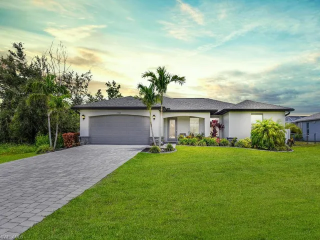 Single story home featuring a lawn and a garage