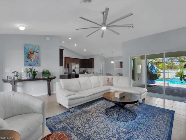 Living room featuring ceiling fan, light tile patterned flooring, and vaulted ceiling