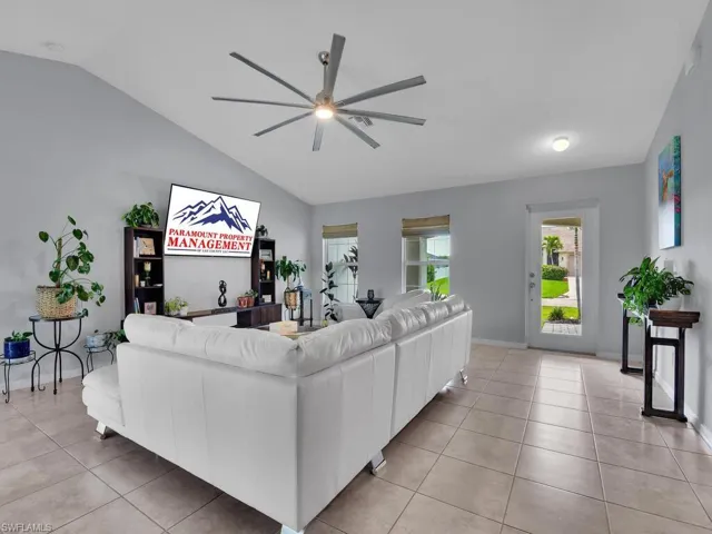 Tiled living room with lofted ceiling and ceiling fan