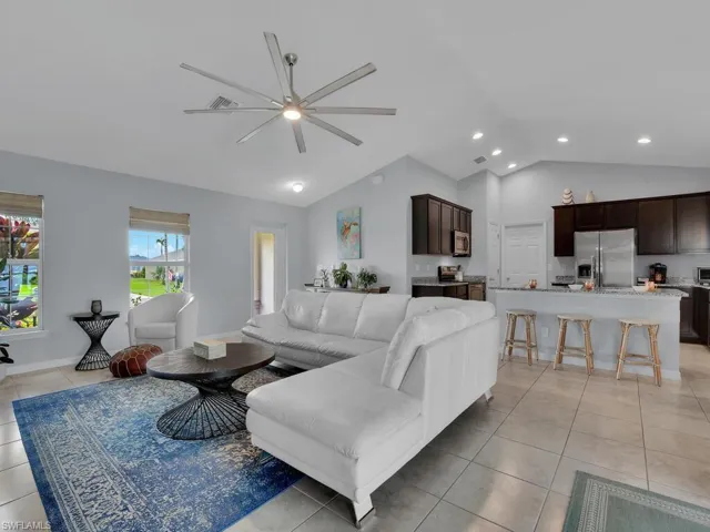 Living room featuring lofted ceiling, ceiling fan, and light tile patterned floors