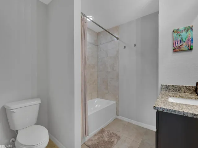Full bathroom featuring vanity, toilet, shower / bathtub combination with curtain, and tile patterned flooring
