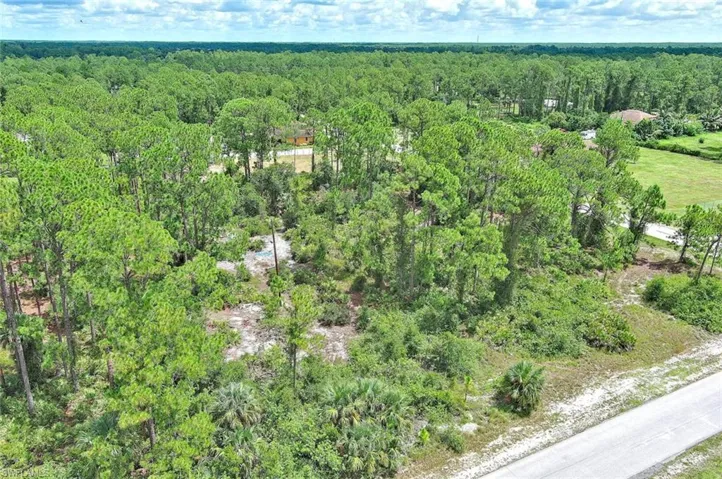Aerial view of property and surrounding area with a heavily wooded area