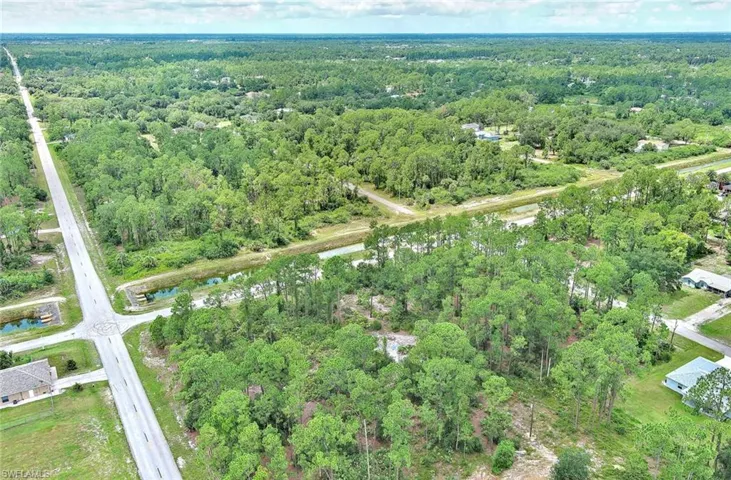 Aerial view of property's location with a nearby body of water and a forest