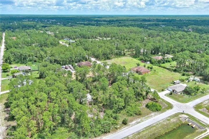 Aerial view of property and surrounding area with a heavily wooded area