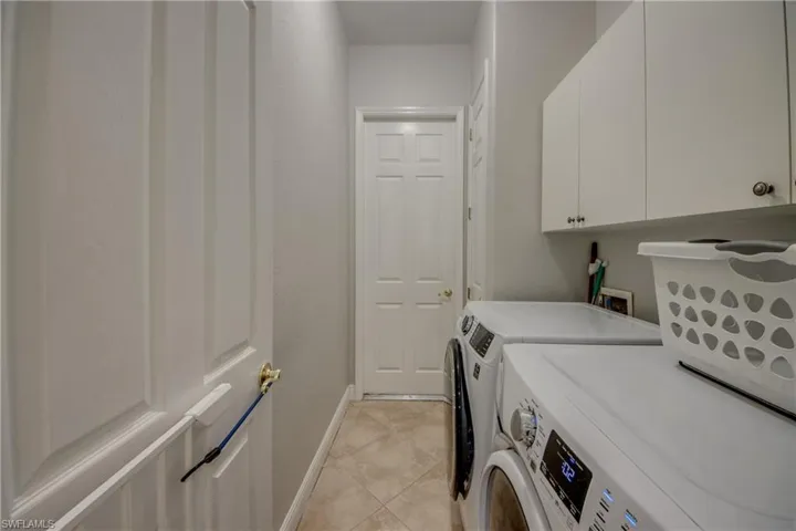 Laundry area with cabinet space, washer and clothes dryer, and light tile patterned flooring