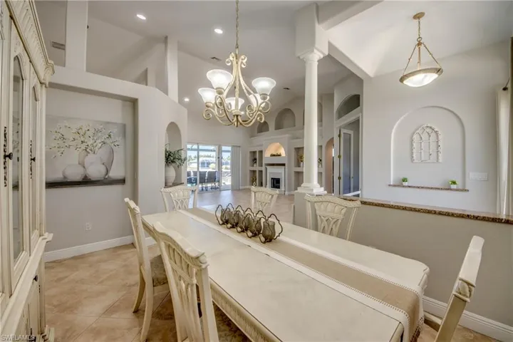 Dining area with built in shelves, lofted ceiling, ornate columns, light tile patterned floors, and suspended lighting