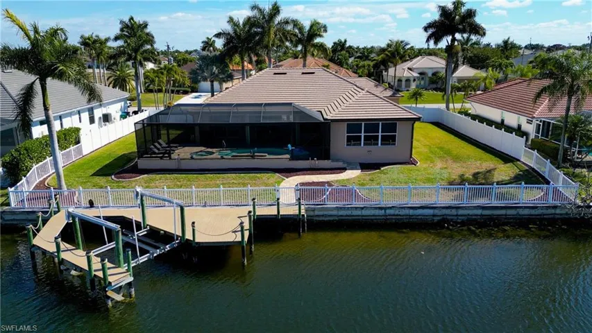 Rear view of house featuring a lanai, a fenced backyard, a sunroom, an outdoor pool, and a water view