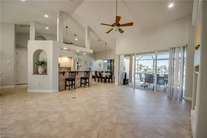 Living room with recessed lighting, ceiling fan, arched walkways, vaulted ceiling, and light tile patterned flooring