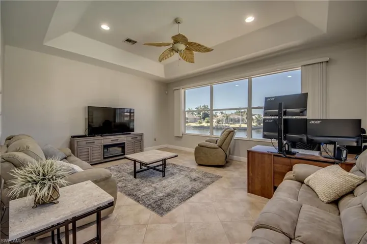 Living area with an office area, a ceiling fan, recessed lighting, a tray ceiling, and light tile patterned floors