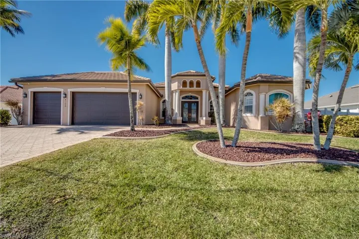 Mediterranean house with french doors, stucco siding, a front lawn, and decorative driveway