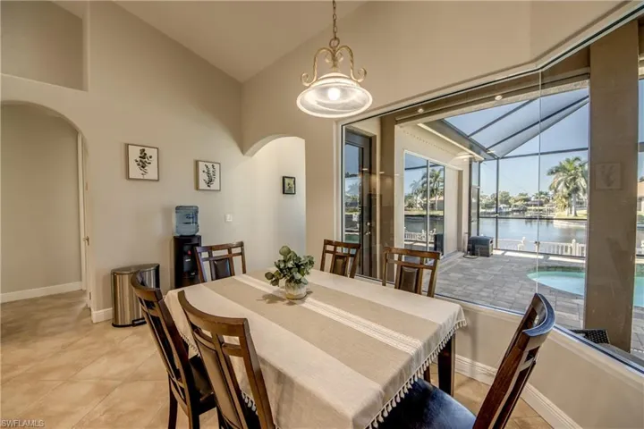 Dining area with vaulted ceiling, arched walkways, a water view, and light tile patterned floors