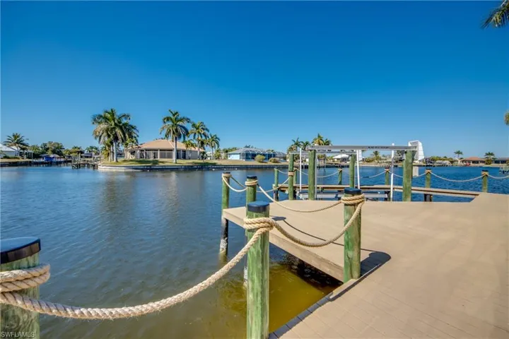 Dock area with boat lift, a water view, and a residential view