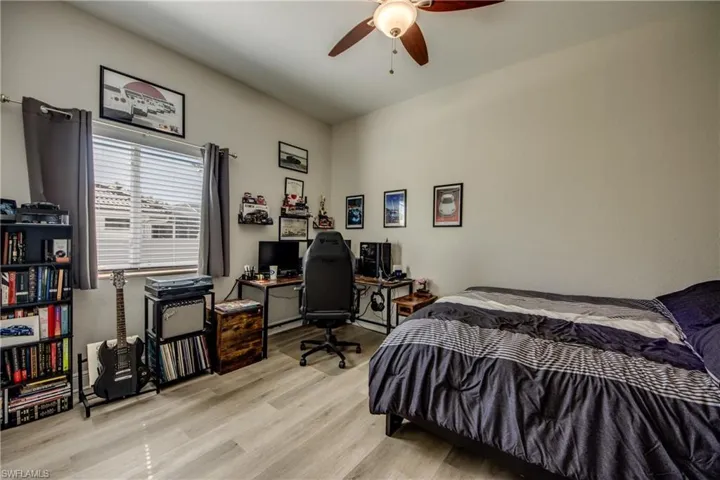 Bedroom featuring a desk, wood finished floors, and a ceiling fan