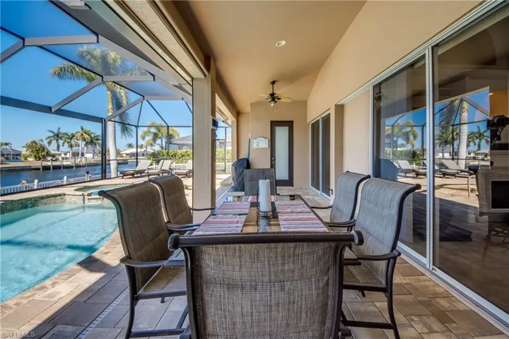 View of patio / terrace with a lanai, a ceiling fan, outdoor dining space and a pool with connected hot tub
