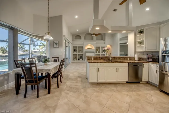 Kitchen featuring ceiling fan, built in shelves, stainless steel appliances, pendant lighting, and dark stone counters