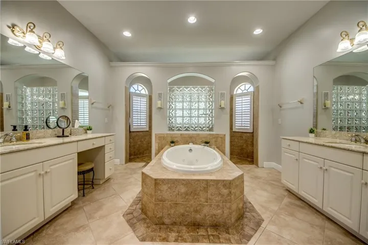 Bathroom with walk in shower, an oversized  jetted tub, and two vanities