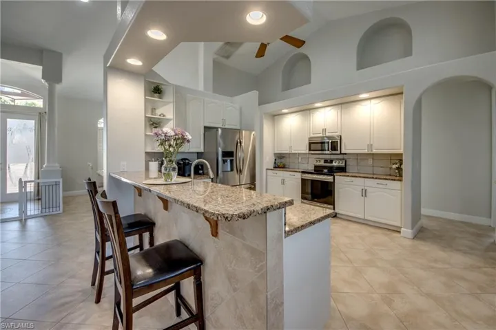 Kitchen with open shelves, a peninsula, ceiling fan, decorative backsplash, and stainless steel appliances
