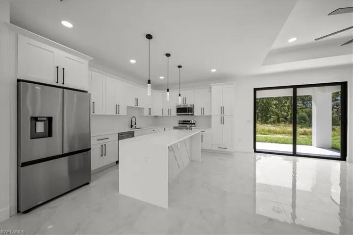 Kitchen featuring stainless steel appliances, light marble finish floors, white cabinetry, decorative light fixtures, and recessed lighting