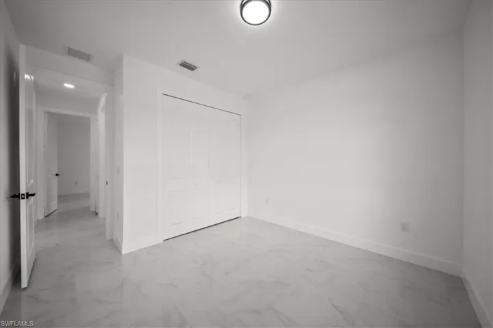 Unfurnished bedroom with light marble finish floors and a closet