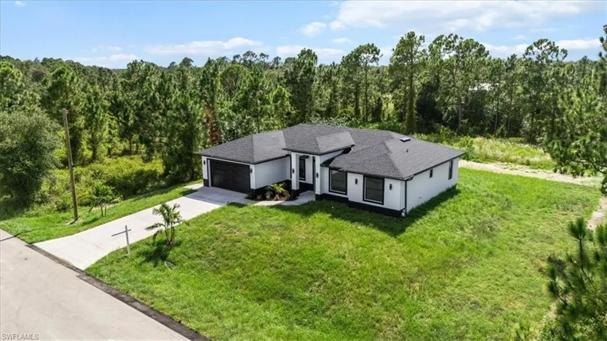 Aerial view of property and surrounding area with a heavily wooded area
