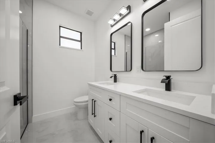 Full bathroom with light marble finish flooring and double vanity