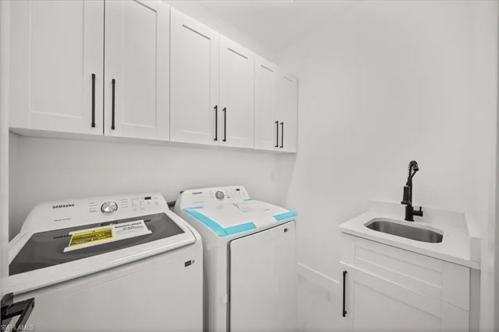 Laundry room with cabinet space, separate washer and dryer, and marble finish floors