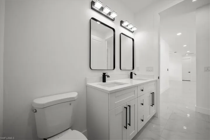 Bathroom with light marble finish flooring, recessed lighting, and double vanity