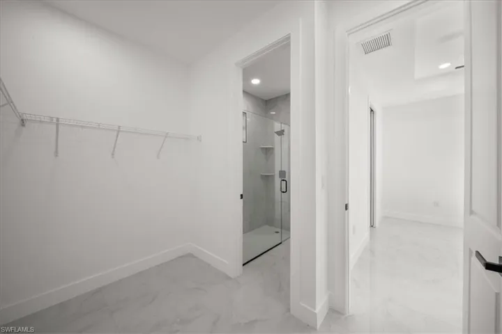 Walk in closet featuring light marble finish floors