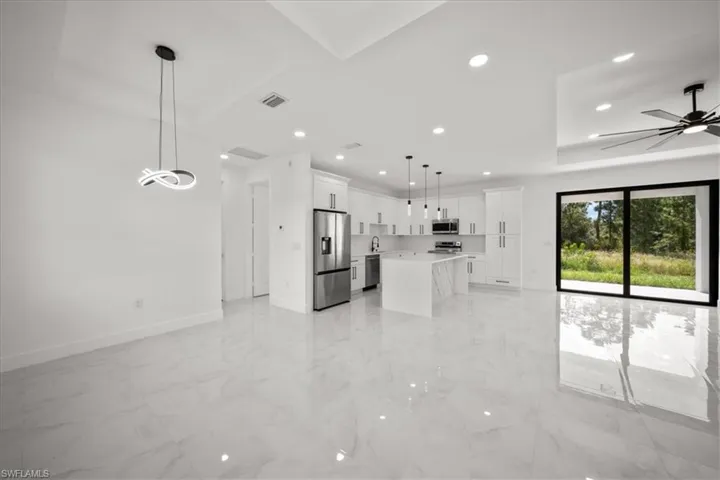 Kitchen with open floor plan, decorative light fixtures, white cabinets, a center island, and recessed lighting
