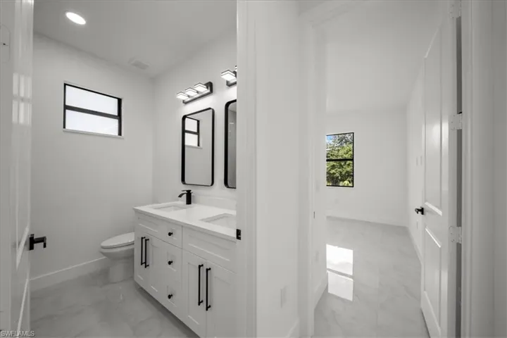 Bathroom with light marble finish flooring, double vanity, and recessed lighting