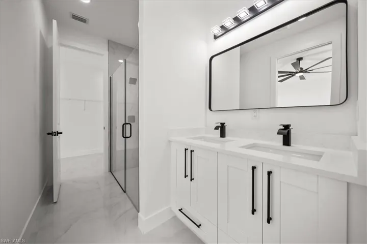 Full bathroom featuring light marble finish floors, double vanity, and a shower stall