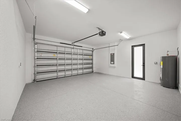 Garage with water heater, electric panel, and a garage door opener