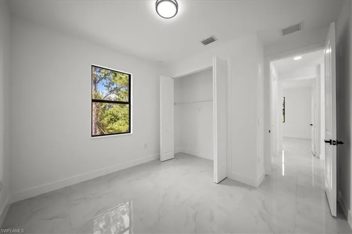 Unfurnished bedroom featuring light marble finish floors and a closet