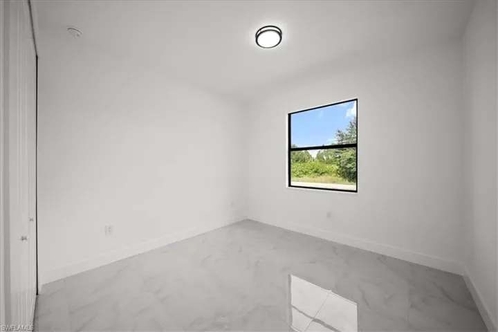 Spare room featuring light marble finish flooring and baseboards