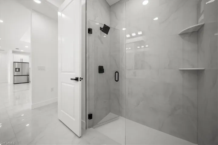 Full bath with a marble finish shower, light marble finish flooring, and recessed lighting
