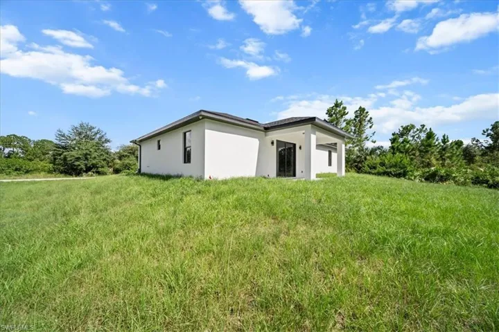 Back of house with stucco siding and a yard