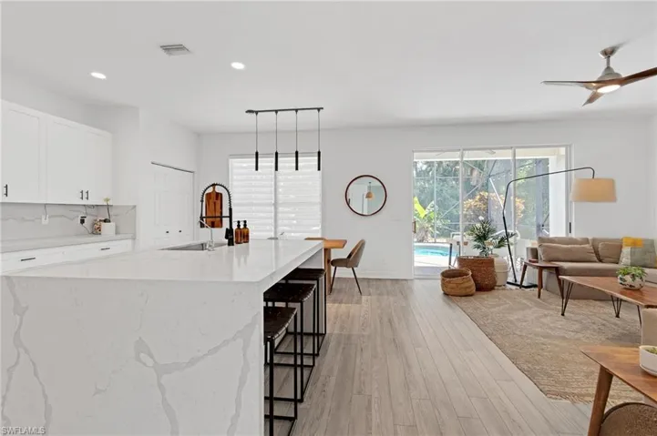 Kitchen featuring decorative light fixtures, white cabinets, light hardwood / wood-style flooring, ceiling fan, and sink