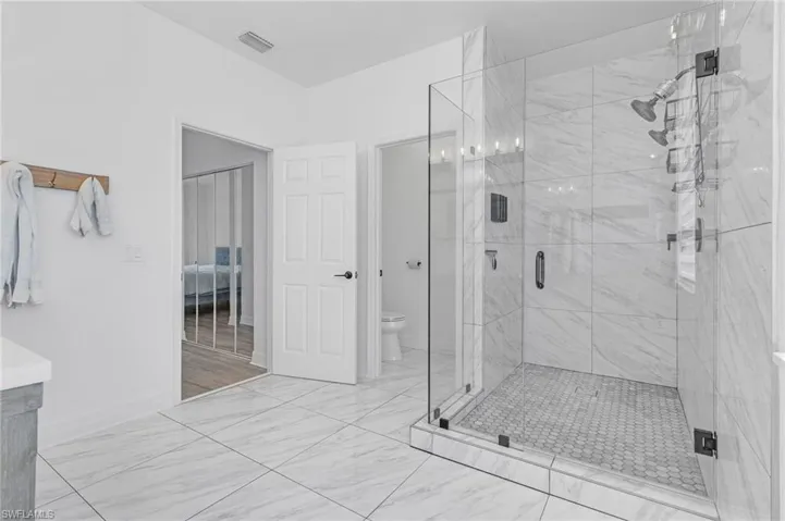 Bathroom featuring a shower with shower door, wood-type flooring, vanity, and toilet