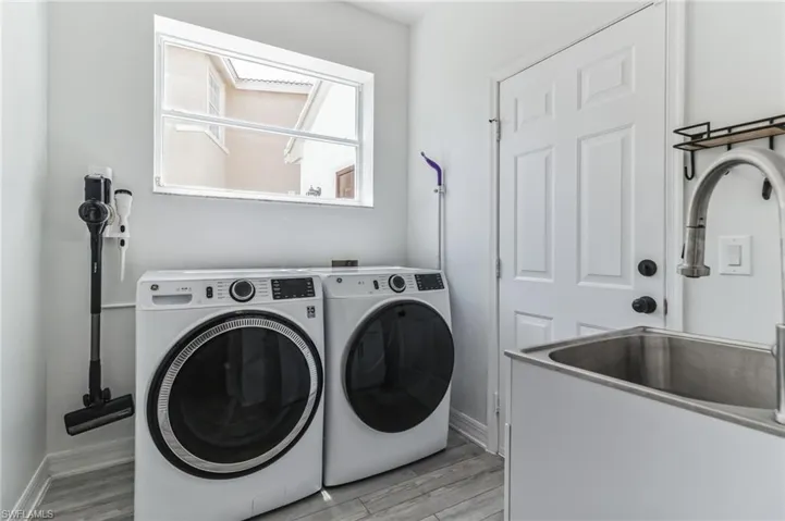 Clothes washing area featuring separate washer and dryer, sink, and light hardwood / wood-style floors