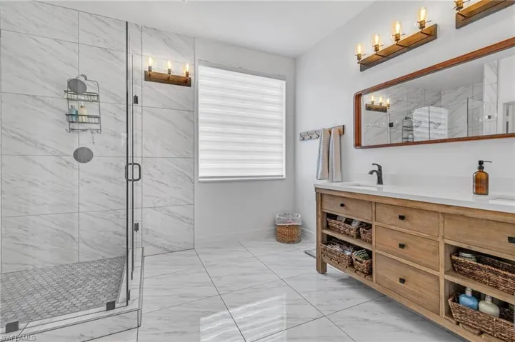 Bathroom featuring tile flooring, a shower with shower door, and vanity