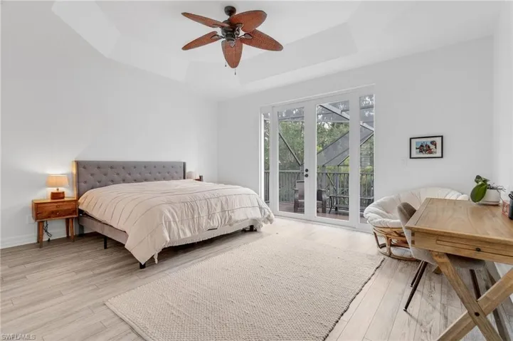 Bedroom with ceiling fan, a raised ceiling, french doors, and access to outside