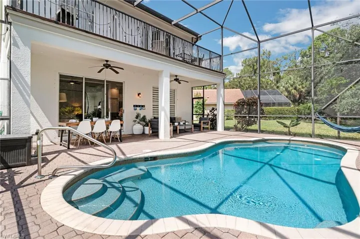 View of pool with a patio area, glass enclosure, and ceiling fan