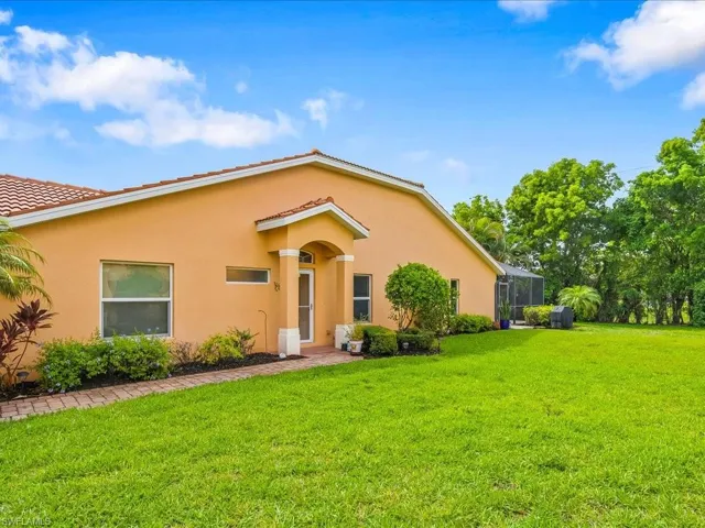 View of front of house with a front lawn, stucco siding, and glass enclosure