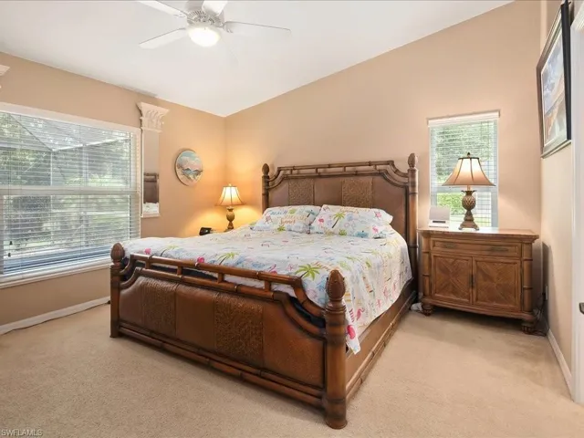Bedroom with light colored carpet, multiple windows, baseboards, and ceiling fan