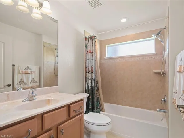 Full bathroom featuring vanity, shower / tub combo with curtain, and toilet