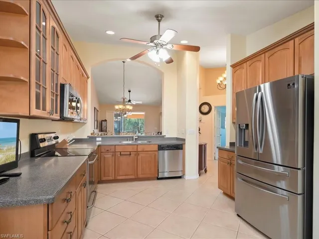 Kitchen featuring appliances with stainless steel finishes, a chandelier, a sink, ceiling fan, and light tile patterned floors