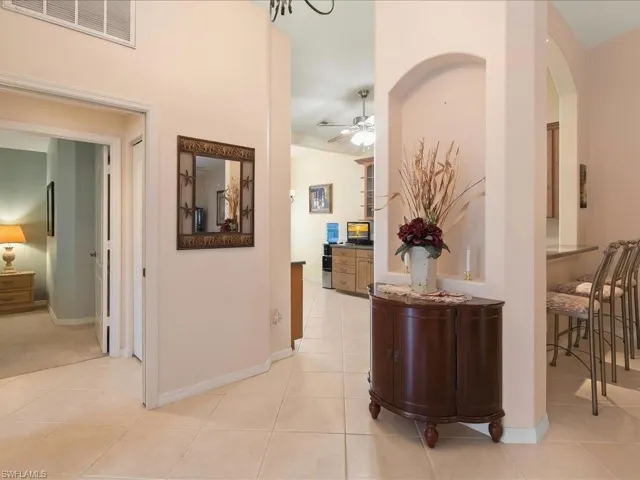 Corridor with light tile patterned floors, arched walkways, and baseboards
