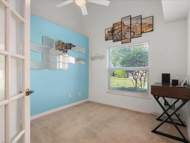 Carpeted office with a ceiling fan and baseboards