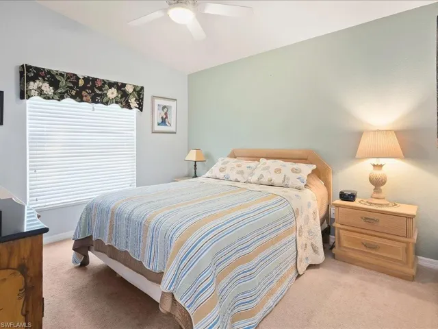 Bedroom with light carpet, vaulted ceiling, baseboards, and a ceiling fan
